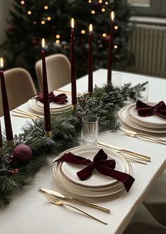 a table set for christmas dinner with place settings and candles in the centerpieces