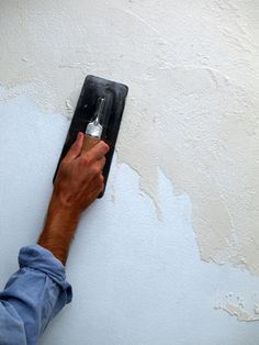 a man is painting the wall with white paint and using a brush to remove it