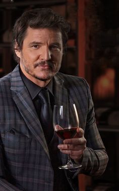 a man in a suit holding a glass of wine