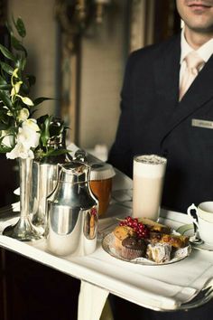 a man in a suit is holding a tray with food and drinks on it,