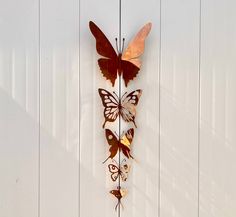 a metal butterfly wall hanging on the side of a white wooden door with three butterflies attached to it