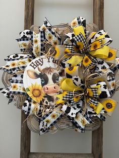 a cow and sunflower wreath on an old wooden chair with the word happy written in it