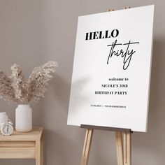 an easel with a hello party sign on it next to a vase filled with flowers