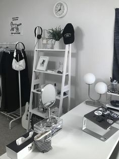 a white desk topped with a mirror next to a shelf filled with clothes and other items