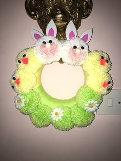 a wreath with two bunny ears hanging from the front of it, next to a light switch