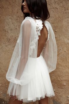 the back of a white dress with sheer sleeves