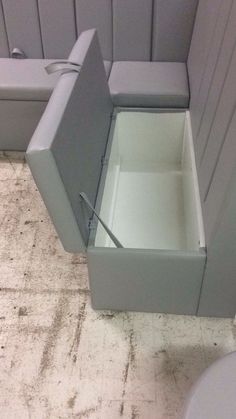 a white toilet sitting next to a gray cabinet on top of a tiled bathroom floor