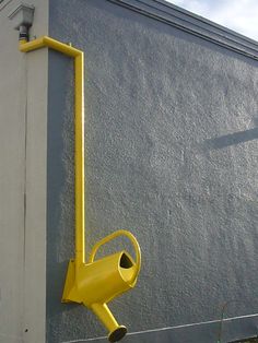 a yellow traffic light mounted to the side of a building next to a grass field