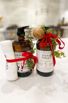 two bottles are sitting on a counter with red ribbon around them and one bottle is filled with liquid