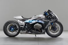 a silver and black motorcycle parked on top of a cement floor next to a wall