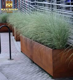 two metal planters with grass in them on the sidewalk