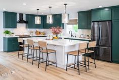 a large kitchen with green cabinets and white counter tops, an island in the middle