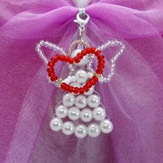 a red and white beaded angel ornament hanging from a purple tulle