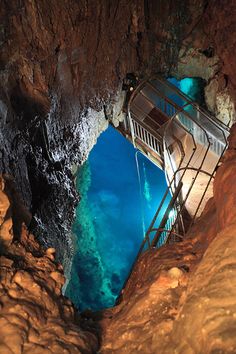 the stairs lead up to an underground cave with blue water and cliffs in the background