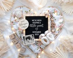 there is a heart shaped frame with baby items in it and the words we've been keeping a little secret