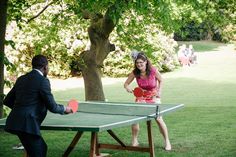 a man and woman playing ping pong in the park