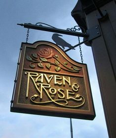 a sign hanging from the side of a building that says raven and rose on it