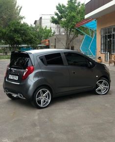 a small gray car parked in front of a building