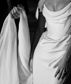 a woman in a white dress is holding onto her wedding gown