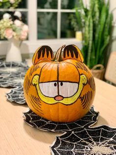 a pumpkin decorated like a tiger sitting on top of a table with spider webs