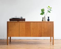 a record player sitting on top of a wooden cabinet next to a potted plant