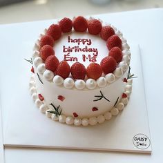 a birthday cake with white frosting and strawberries on top that says happy birthday em mi