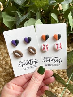 two small pins with baseballs on them are being held up by someone's hand