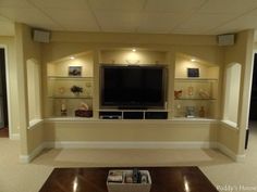 an empty living room with built in shelves and a flat screen tv on the wall