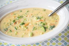 a white bowl filled with broccoli and cheese soup on top of a table