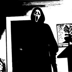 a black and white image of a person wearing a mask in front of a mirror