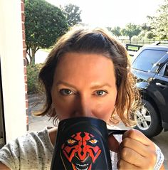 a woman is drinking from a coffee mug