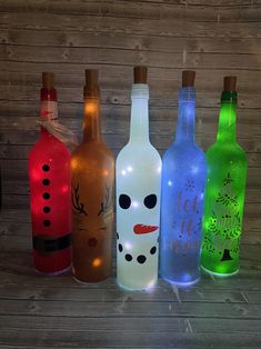 four lighted bottles with faces on them sitting next to each other