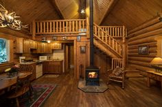 the inside of a log cabin with wood floors and stairs leading up to a loft