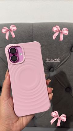 a person holding a pink phone case in front of a couch with bows on it