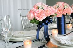 the table is set with pink roses in vases and place settings for dinner guests