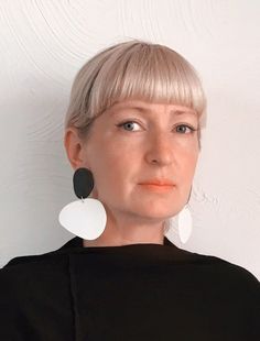 a woman with blonde hair wearing large white and black earrings on her ears