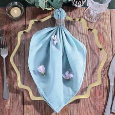 a blue napkin sitting on top of a wooden table next to silverware and utensils