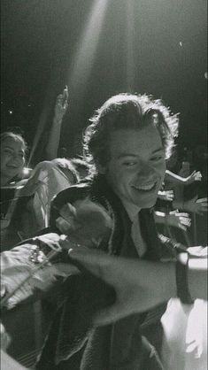 a black and white photo of a man laughing in front of some other people at a concert