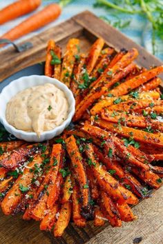 grilled carrots on a wooden platter with dipping sauce