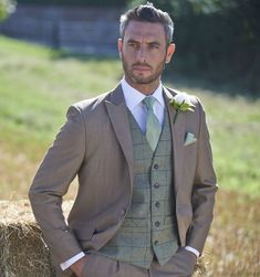 a man in a suit standing next to hay bales with his hands on his hips