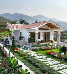 a white house with lots of flowers and greenery on the front lawn, surrounded by mountains