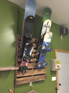 two snowboards mounted to the side of a wooden pallet in a green room