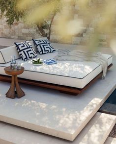 a bed sitting on top of a white floor next to a pool with trees in the background