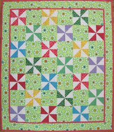 a green quilt with red trim and white flowers on the bottom, along with an orange border