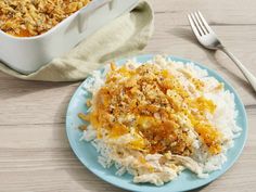 a blue plate topped with rice covered in toppings next to a casserole dish