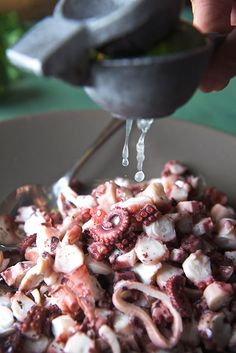 someone is pouring something into a bowl full of food