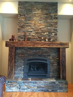 a living room with a stone fireplace and wooden mantle