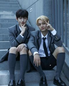 two boys in suits sitting on steps with their hands to their faces and one boy wearing glasses