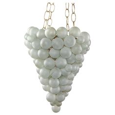 a cluster of white beads hangs from a gold - plated chain on a white background