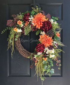 a wreath on the front door with flowers and greenery hanging from it's side